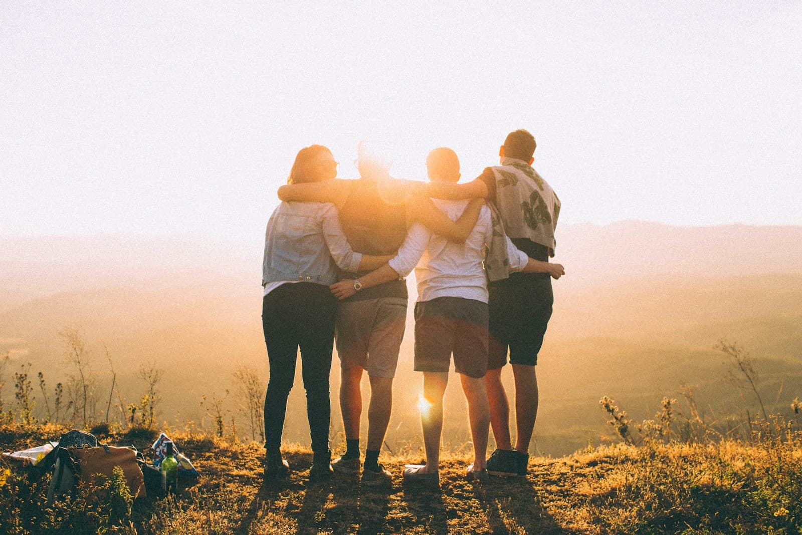 Four people with arms around each other looking at sunset